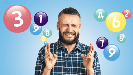 Man crossing his fingers in front of lottery number balls